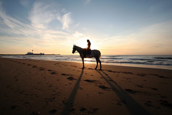 Menina em um cavalo no fundo do pôr do sol