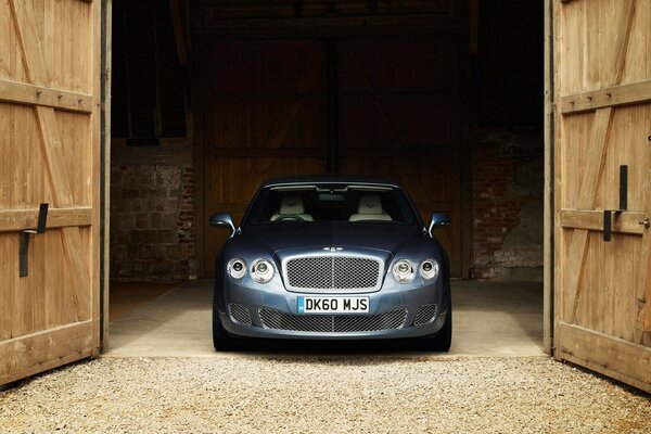 Bentley est debout dans le garage et la porte est ouverte