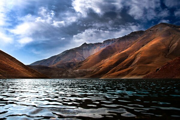 Un lago en las montañas ondulaciones poco profundas corriendo sobre el agua después de las nubes pesadas que huyen