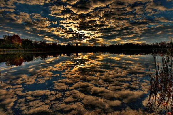 Schöner Sonnenuntergang durch Wolken, die sich im See widerspiegeln