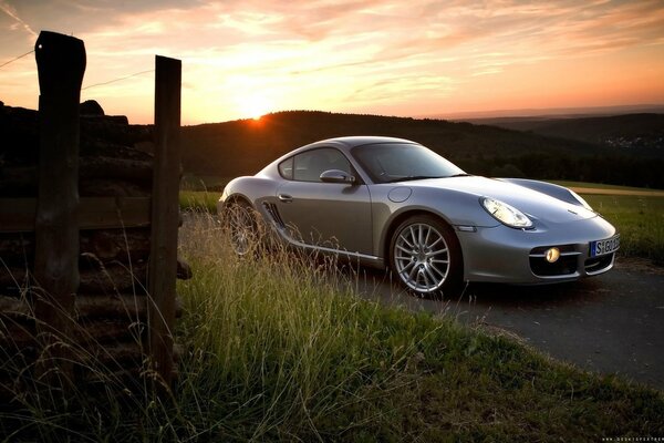 Серый Porsche cayman на закате