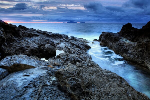 Pôr do sol frio na costa rochosa do oceano