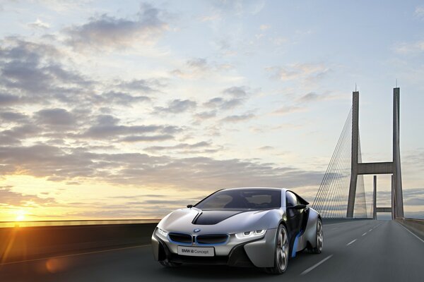 El coche en el puente viaja en medio de la puesta de sol