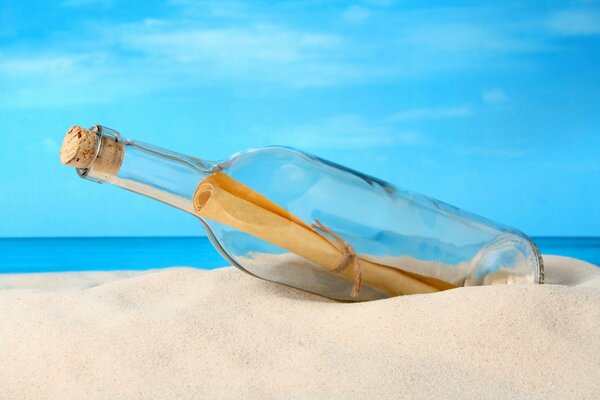 Flasche mit Brief im Sand auf dem Hintergrund des Meeres