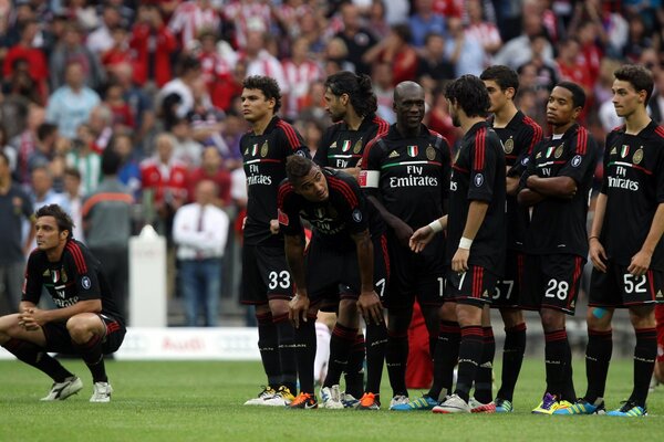 A team of black-uniformed football players is waiting for something