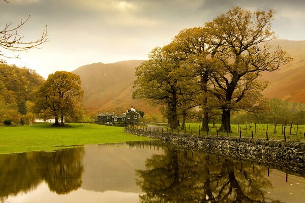 Landschaft mit See, Haus und Bäumen im Morgengrauen