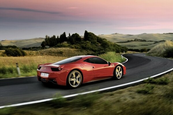 Un Ferrari de color rojo que corre por la carretera entre los campos