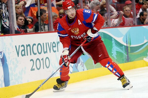 A hockey player on the ice of the stadium getting ready to throw