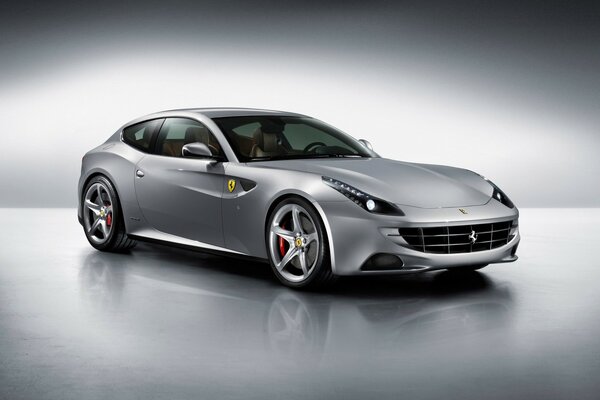 Coche Ferrari de color gris, de pie sobre una superficie reflectante