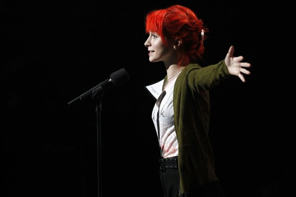 A girl sings with a microphone on stage