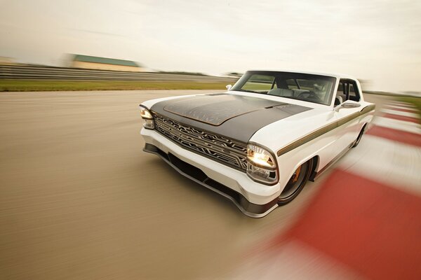 A two-tone Chevrolet is standing on the road near the crossing