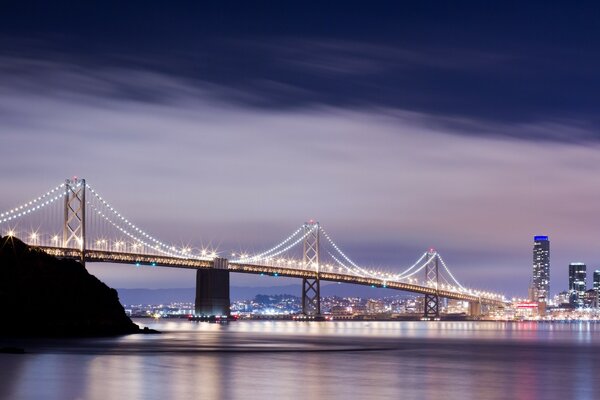 The bridge is all in lights across the river to the city