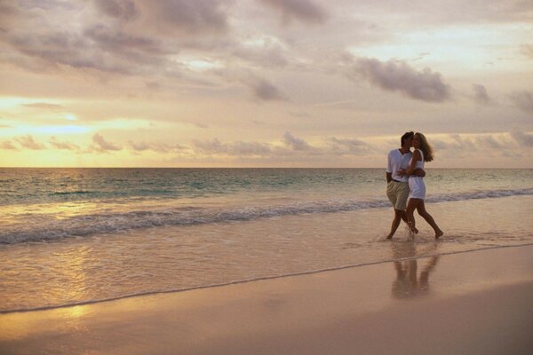 Coppia che cammina sulla spiaggia al tramonto