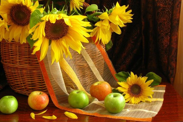 Girasoles en una canasta sobre una mesa con manzanas