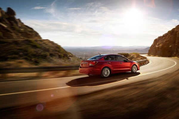 Subaru rojo corre hacia el sol