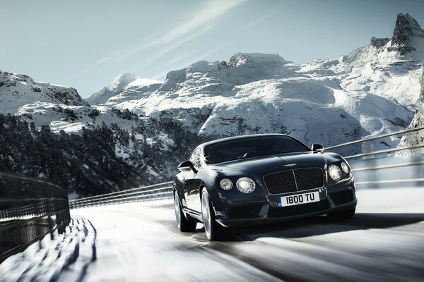 Bentley noir sur l autoroute en hiver. Sur le fond des montagnes et du ciel