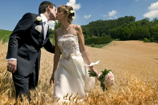 The newlyweds kiss in the middle of the field