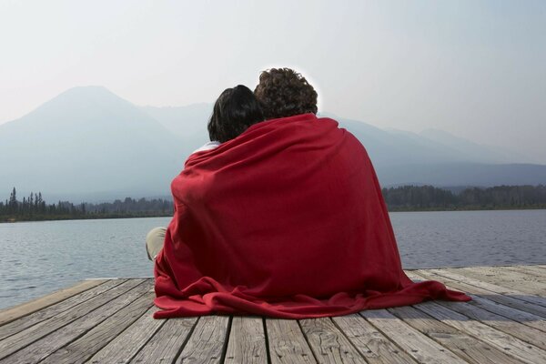 Dos amantes en el muelle bajo una manta roja