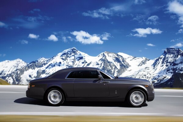 The car rushes along the road against the background of snowy peaks