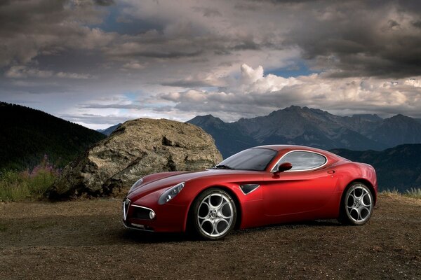 COUPÉ ALFA ROMEO SUR UNE CLAIRIÈRE DANS LES MONTAGNES