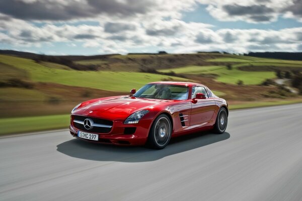 El coche rojo brillante conduce a la velocidad en la carretera perfecta