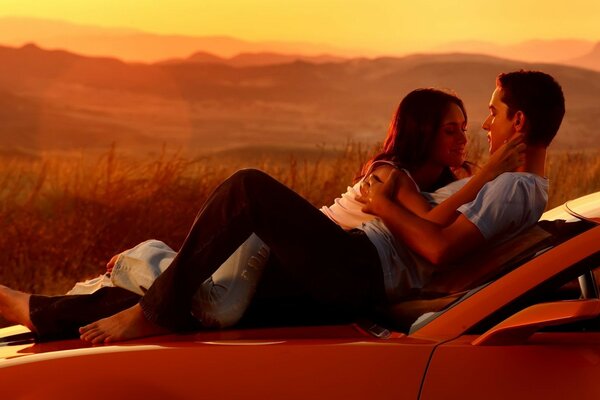 Fiction about adults on the hood of a car at sunset