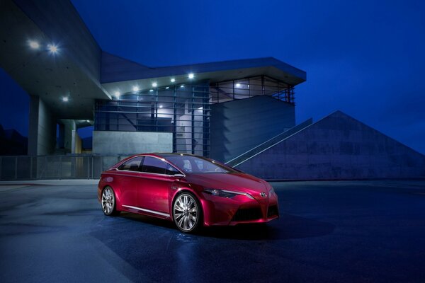 Coche rojo brillante en el fondo de la casa por la noche