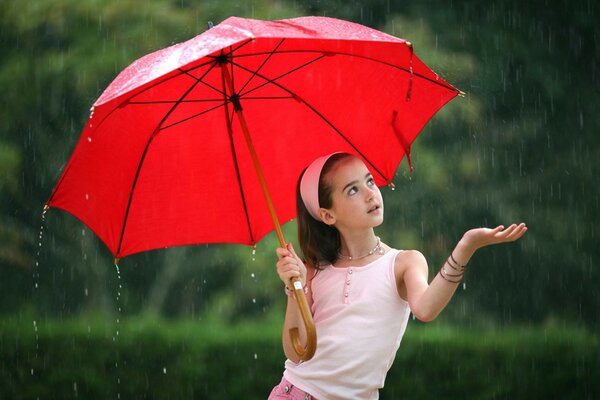 Mignonne petite fille avec un parapluie rouge sous la pluie