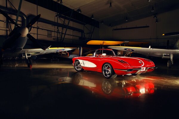 An old chevrolet supercar near the plane