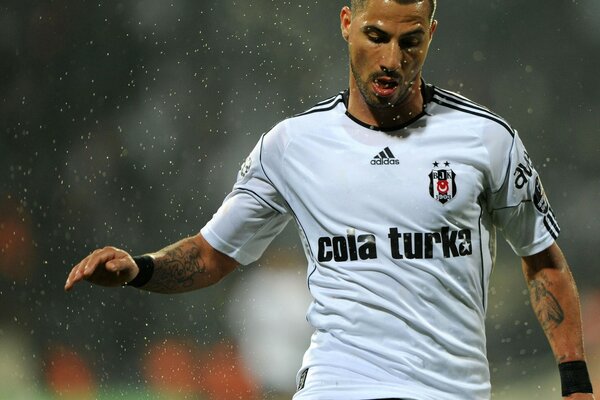 Jogador de futebol na chuva em uniforme branco