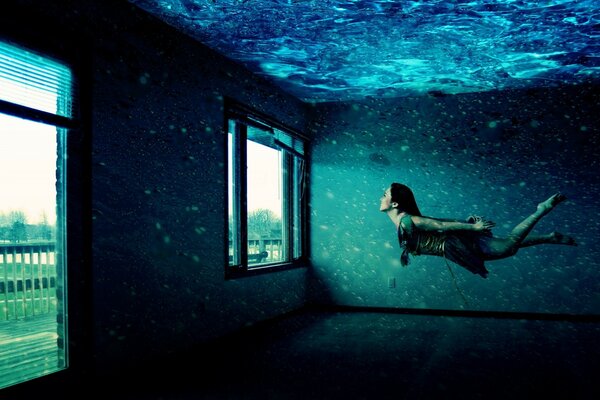 فتاة تسبح تحت الماء في غرفة بها نوافذ