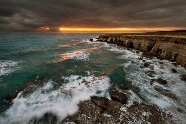 Waves crashing against rocks. Sunset on the background of the sea