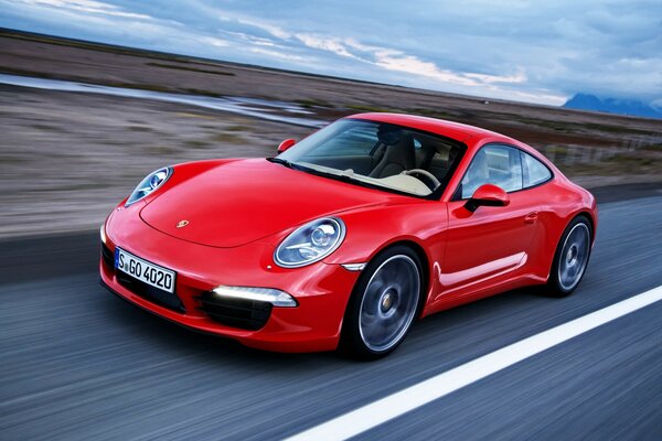 Porsche rojo corre sobre el asfalto