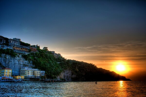 Pôr do sol à beira-mar com casas nas rochas