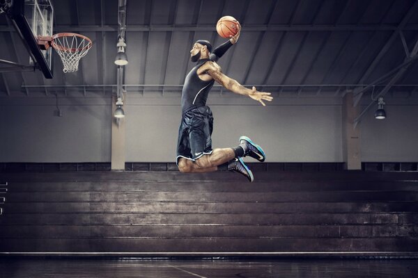 A basketball player throws the ball into the basket in a jump