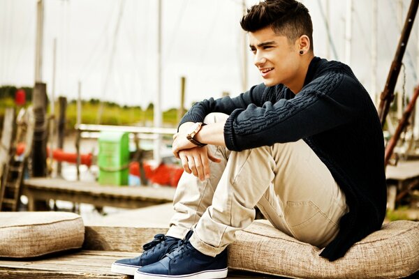 A young man is sitting on the pier