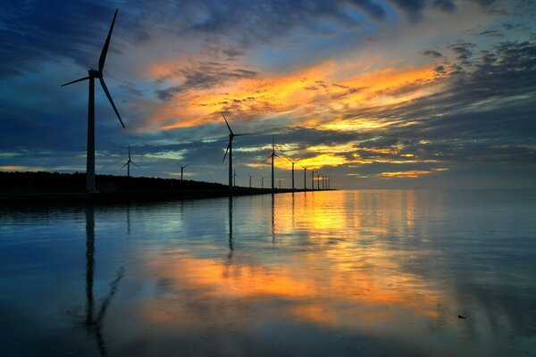 Sunset reflected in the water with windmills on the shore