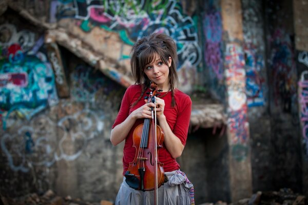 Violinista en rojo contra fondo de pared con graffiti
