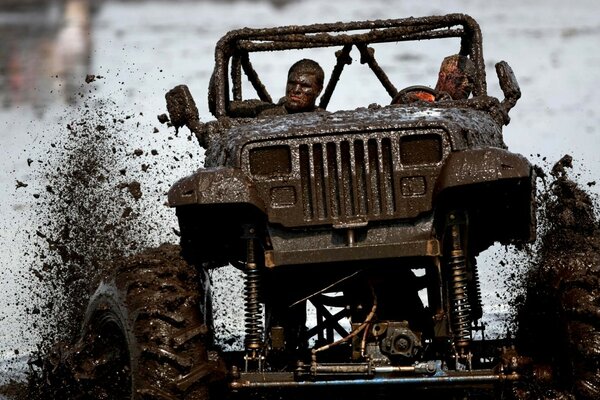 Two men driving a futuristic jeep through the mud