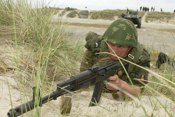 Un soldado con un rifle de asalto en un casco yace