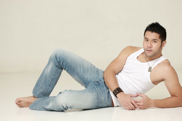 A man poses on the floor on a light background