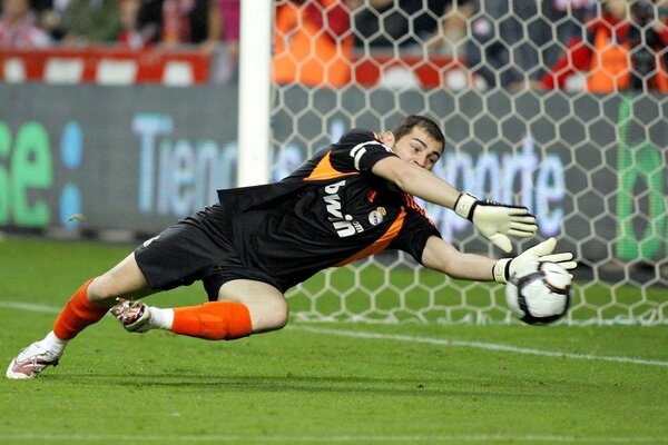 The goalkeeper catches the ball on the football field