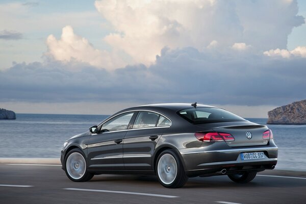 Volkswagen car drives along the highway along the ocean