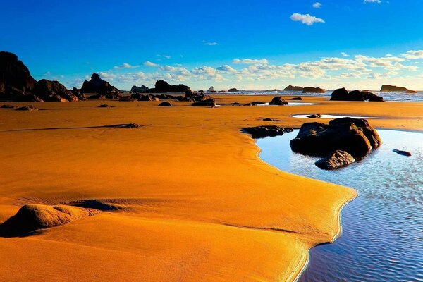 Wasser am Sand und bewölkter Himmel