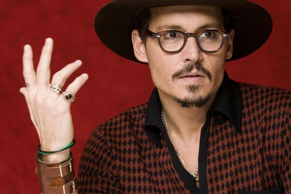 Actor in a hat and glasses on a red background