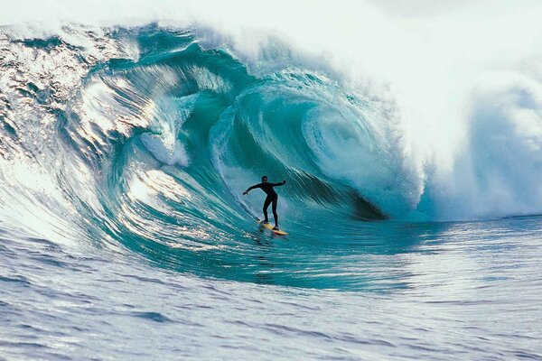 Eine faszinierende türkisfarbene Meereswelle umhüllt den Surfer