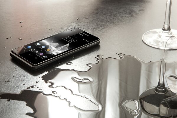 Sony s smartphone near the spilled water on the table