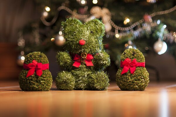 Cute toys made of pine needles decorated with pink bows on the background of a Christmas tree