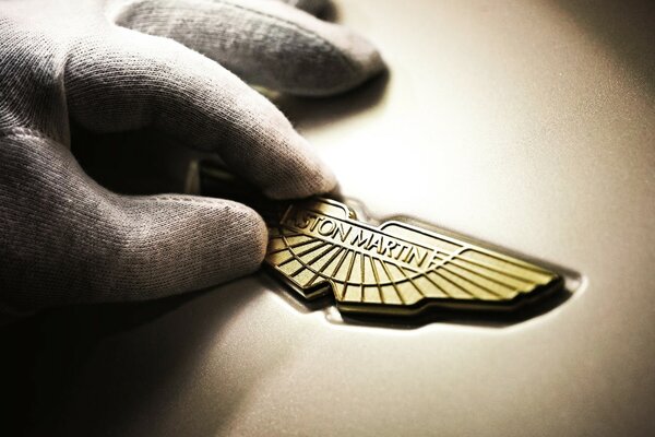 A man s hand holds a car badge