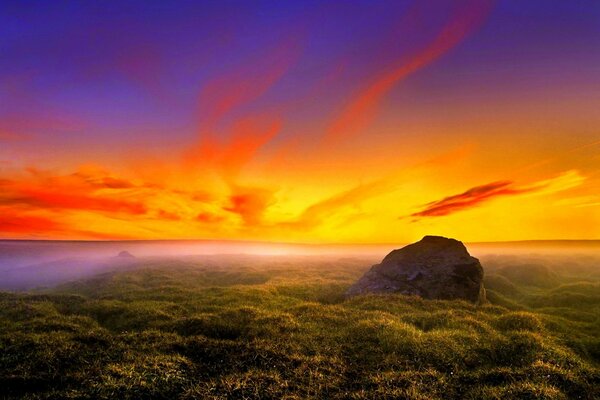 A misty sunset is greeted by boulders